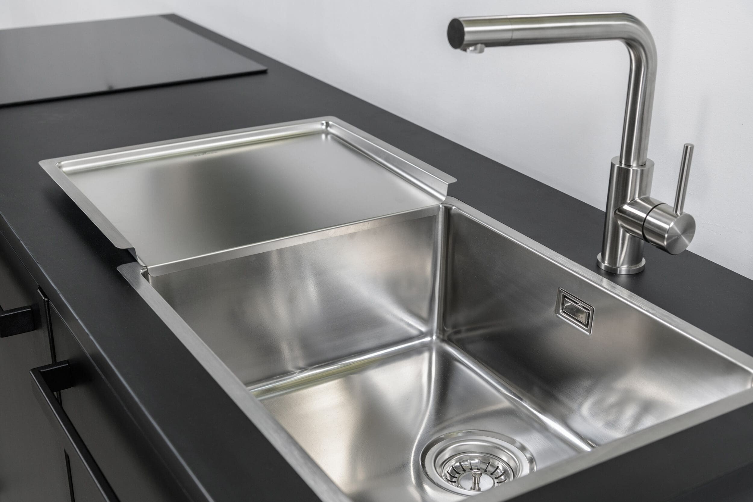 Zwarte keuken met grote RVS spoelbak en kraan